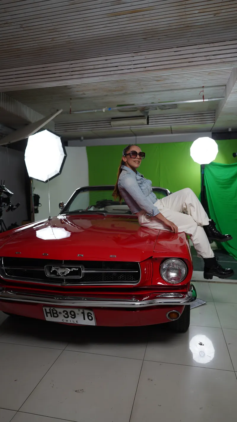 An actress poses on the Mustang's hood in front of a green screen